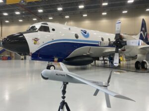 A model of an Altius uncrewed aircraft system with NOAA WP-3D Orion N42RF, nicknamed "Miss Piggy," in the background at the NOAA Aircraft Operations Center in Lakeland, Florida.