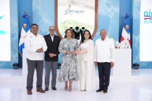 La diseñadora Gisselle Mancebo recibe el reconocimiento de manos de representantes del Ministerio de Energía y Minas.