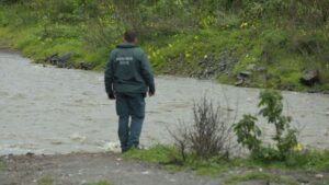 Un agente de la Guardia Civil busca a una mujer desaparecida en un río durante el temporal. | EFE